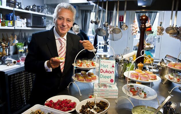 Pierre Dukan está rodeado de platos dietéticos. 